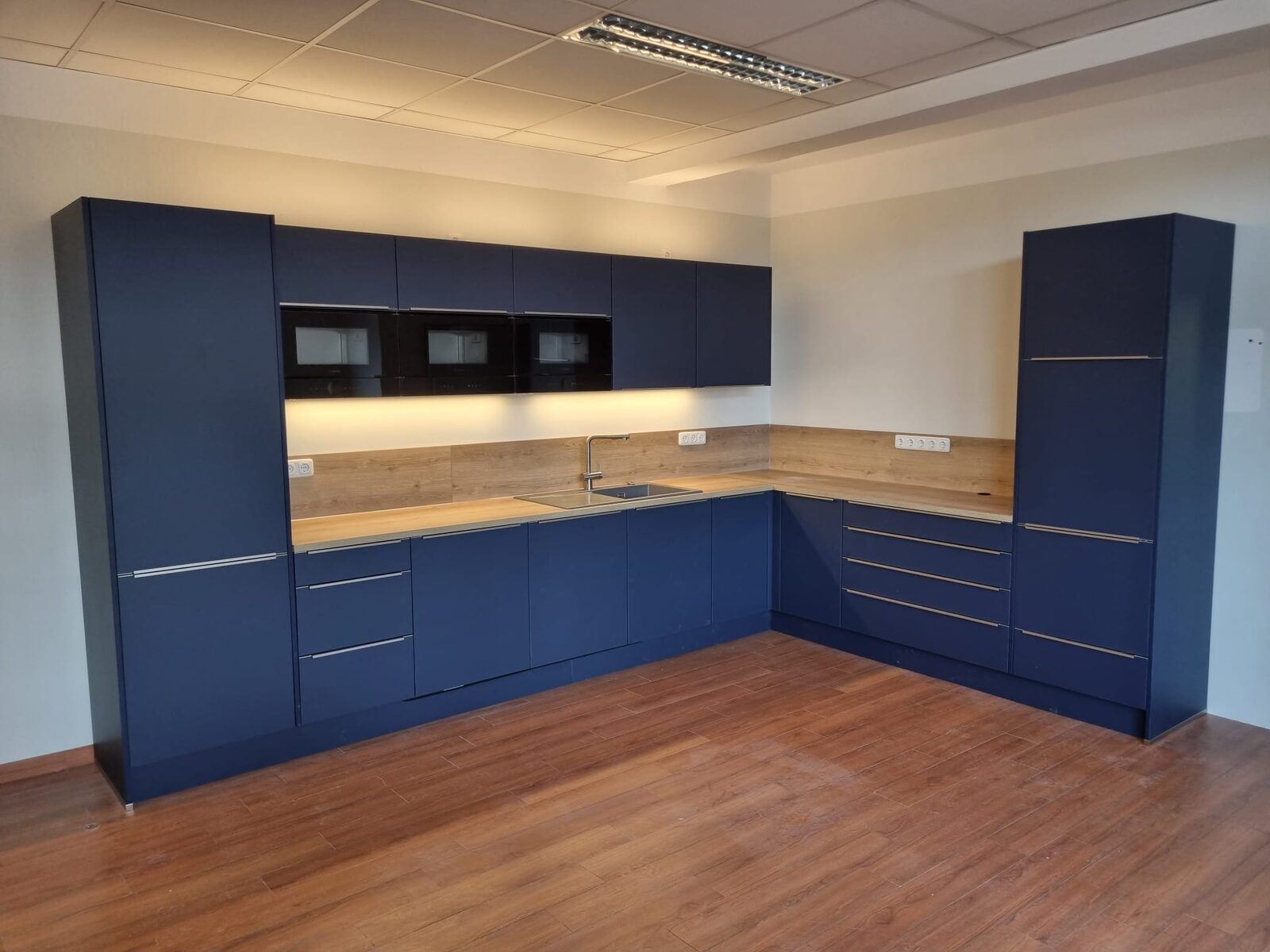 Dunkelblaue L-Küche mit Hochschränken und Holz-Arbeitsplatte